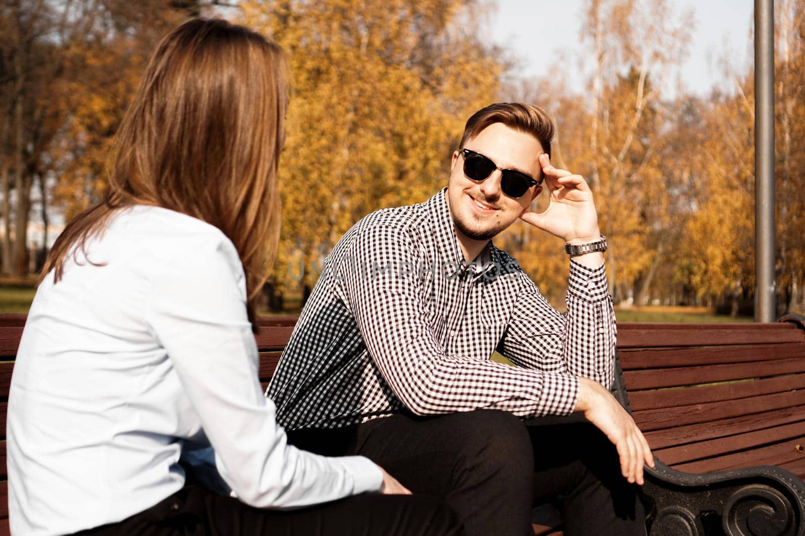 Happy smiling couple on park bench in fall sunny day