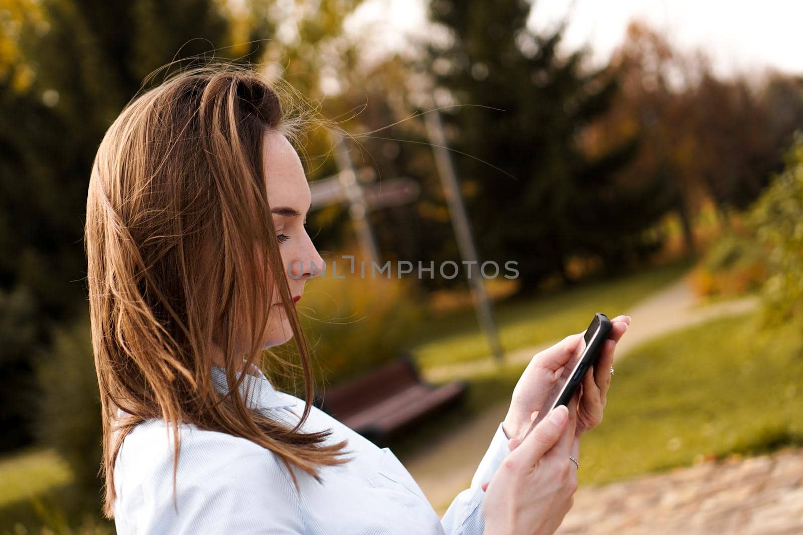 Woman using mobile smart phone in the park.