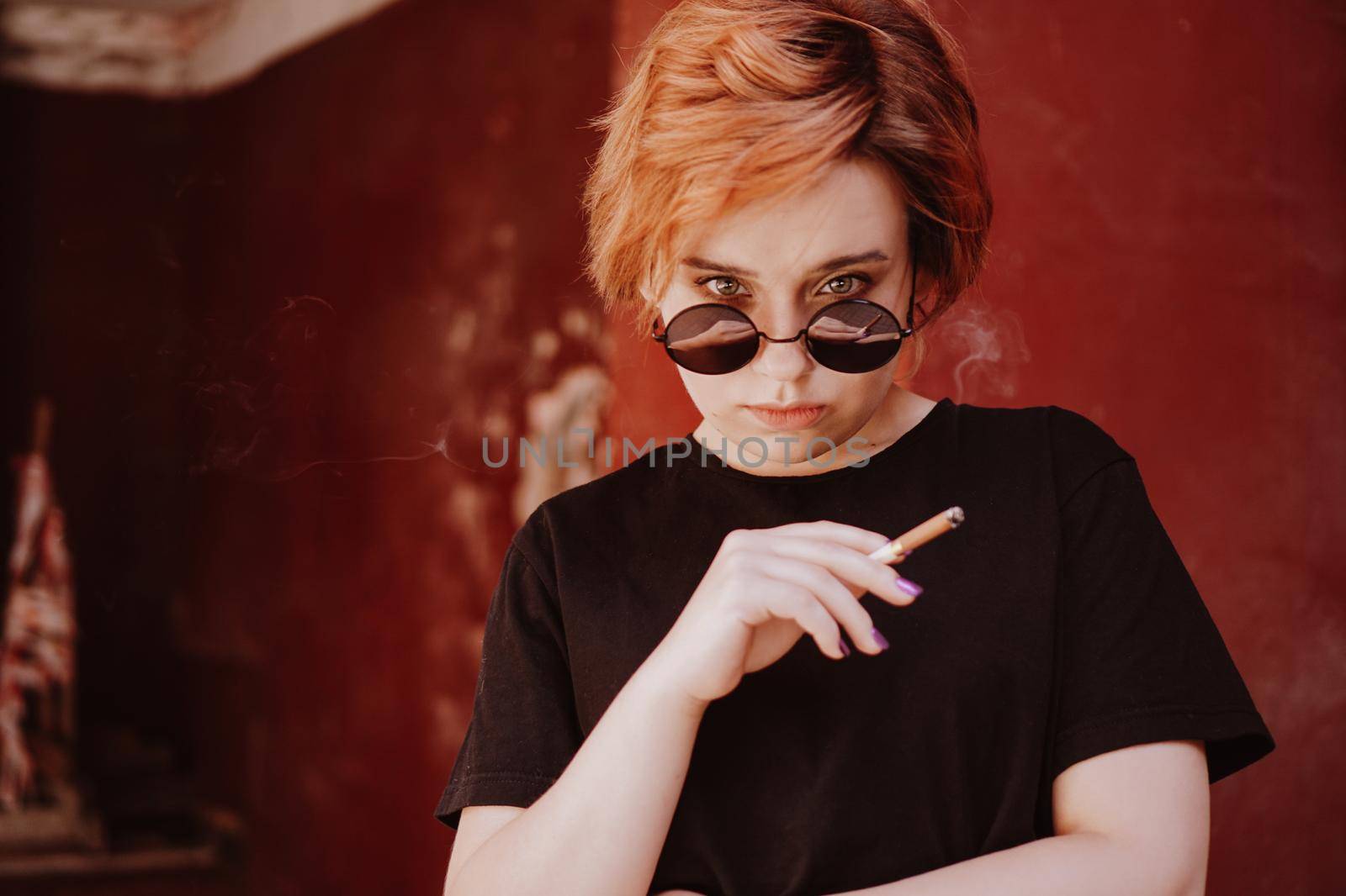 Millennial girl with short red hair and mirror sunglasses smoking cigarette by natali_brill