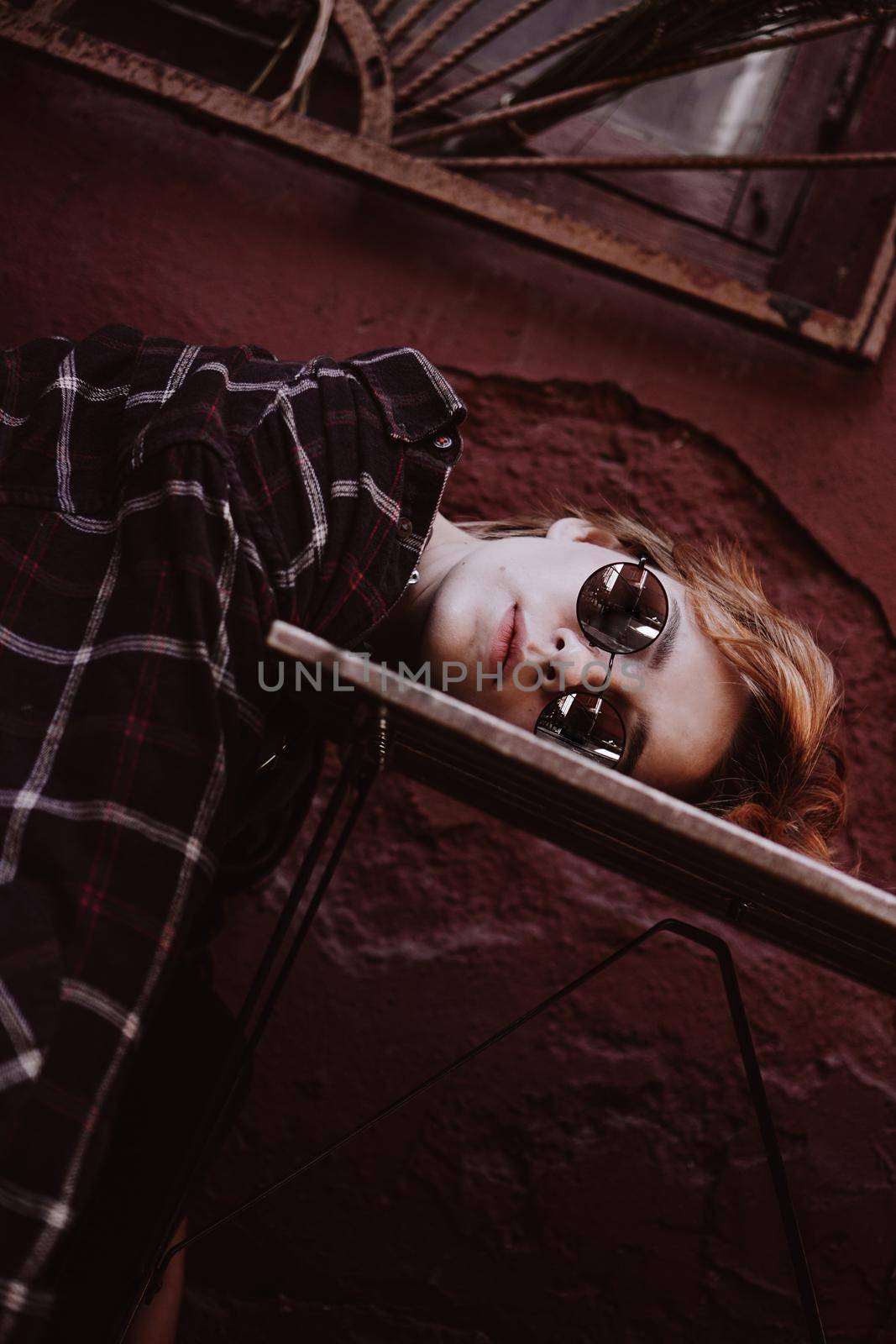 Portrait of woman with short red hair in sunglasses, head lies on table by natali_brill