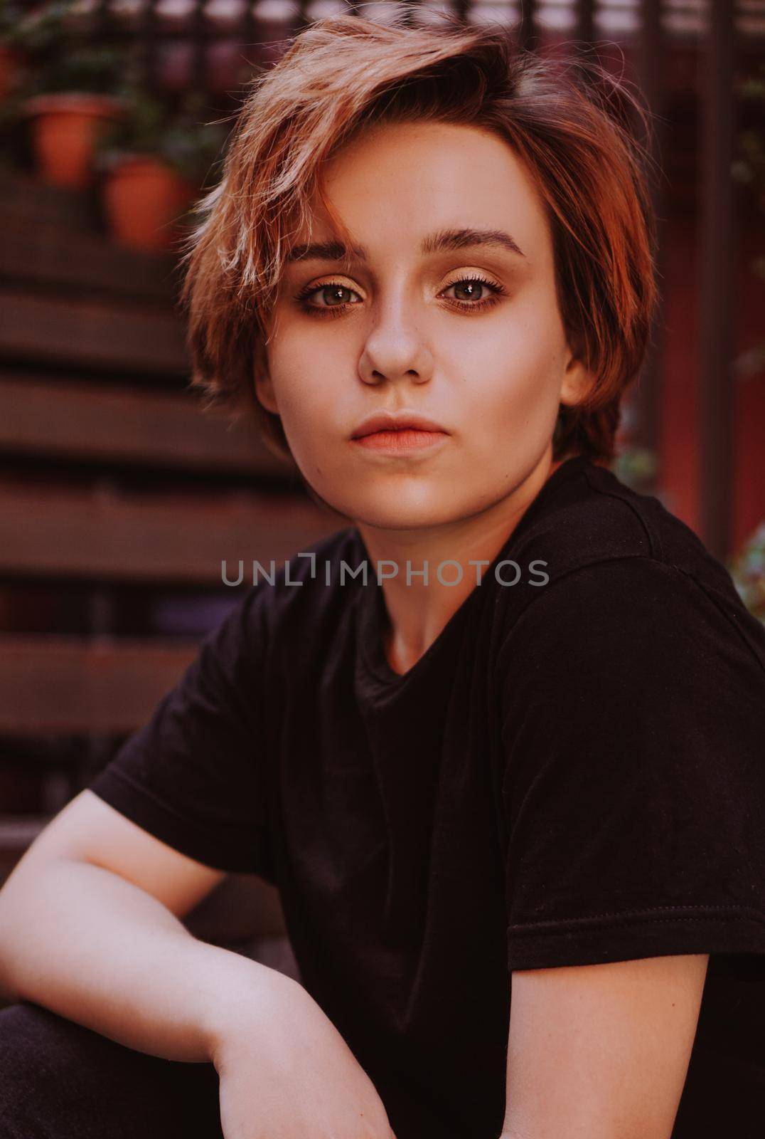 Portrait of attractive cheeky woman with short red hair at back yard in the old city with red walls