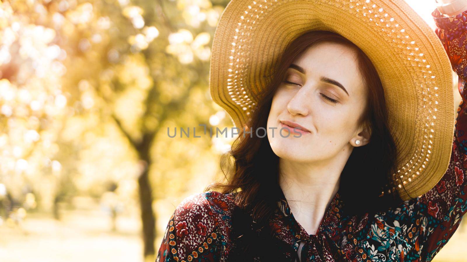 Summer portrait, beautiful young woman wearing straw hat at sunset time on the garden