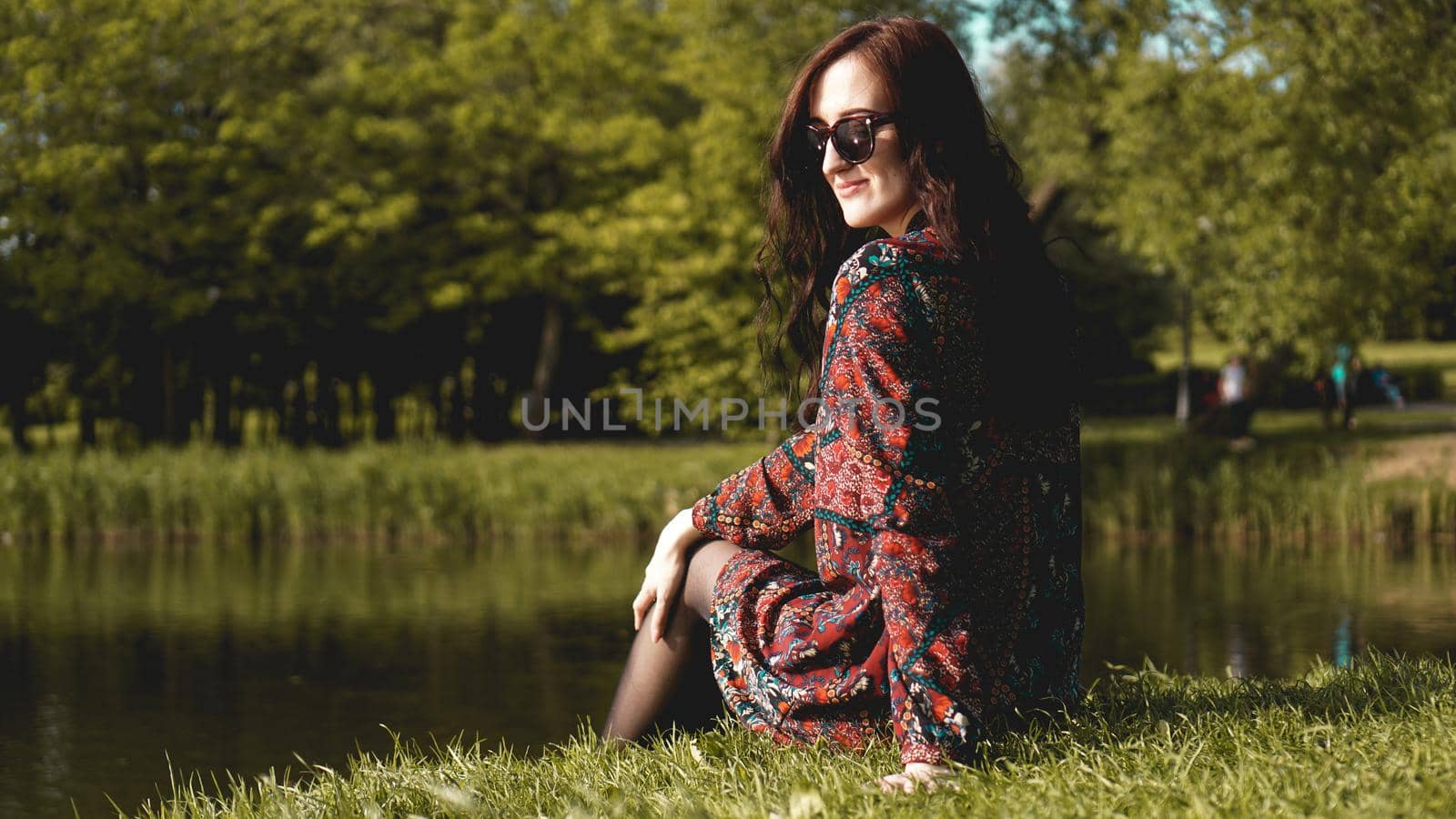 Portrait of woman in profile in sunglasses resting on the nature near the river.