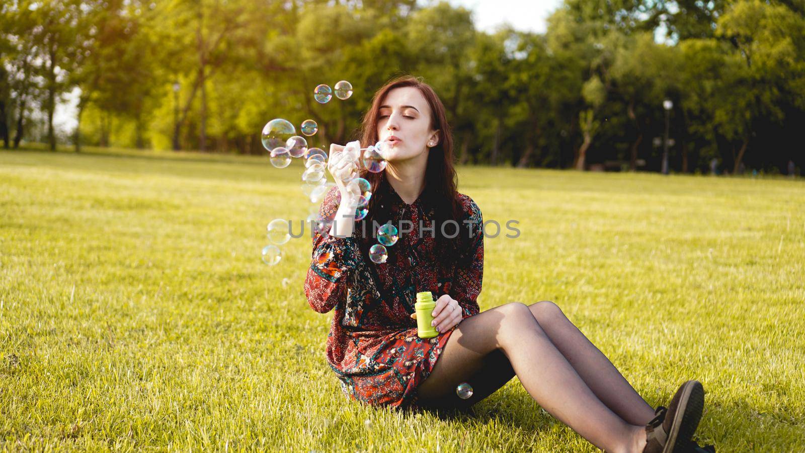 Romantic portrait of young woman with soap balloons. Sunny Valley on a summer day