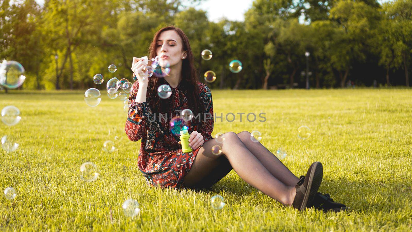 Romantic portrait of young woman with soap balloons. Sunny Valley on a summer day
