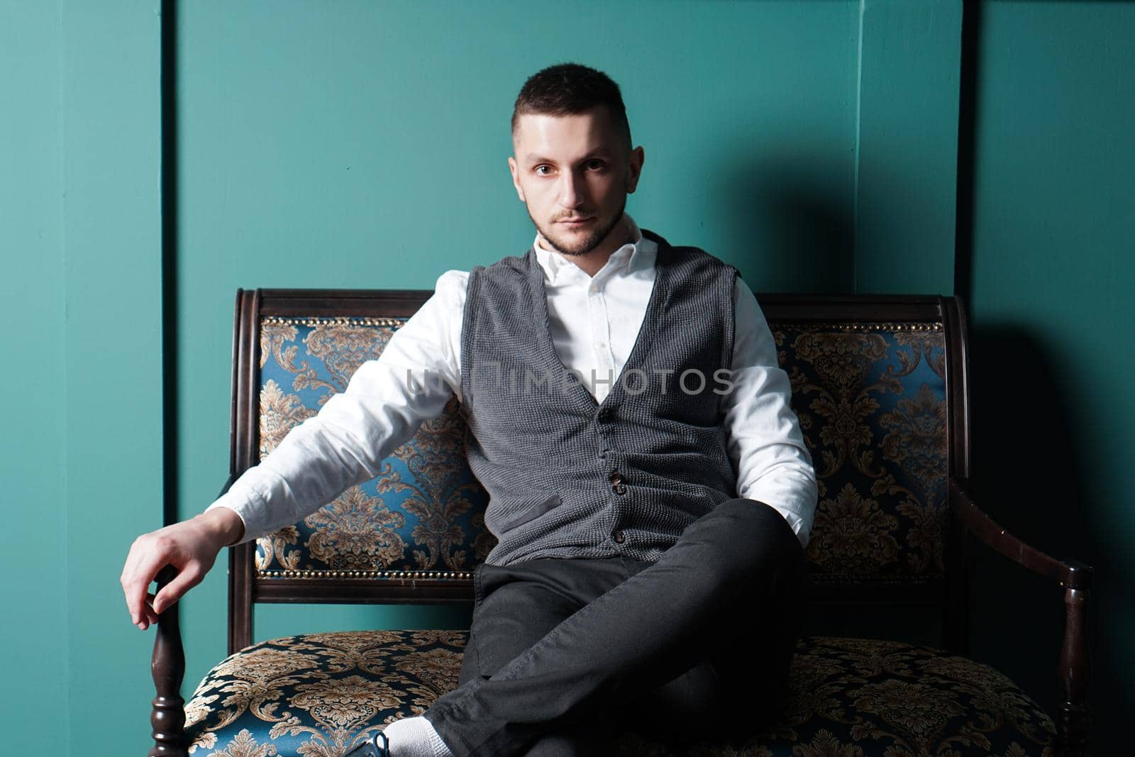 Portrait handsome fashionable man in a white shirt sits on a chair in a studio by natali_brill