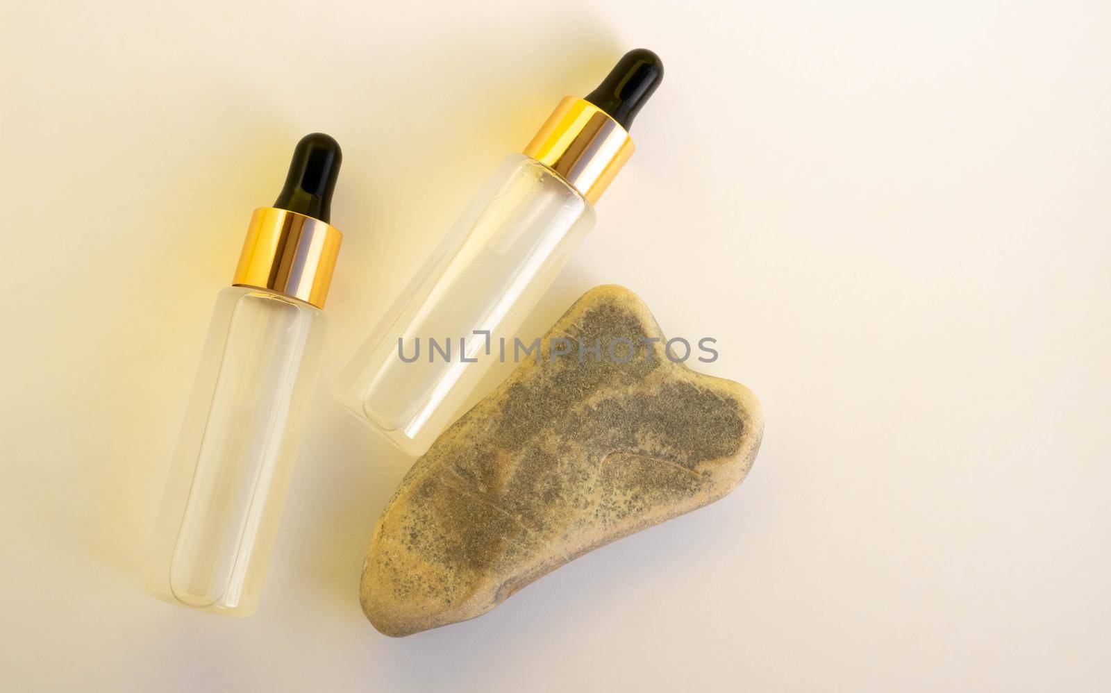 Two bottles of cosmetic liquid transparent gel next to a gray heart-shaped stone on a white background. Flat styling style.