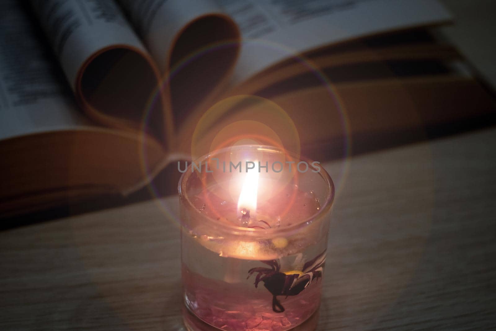 Bright candle in the dark against the background of the book close up