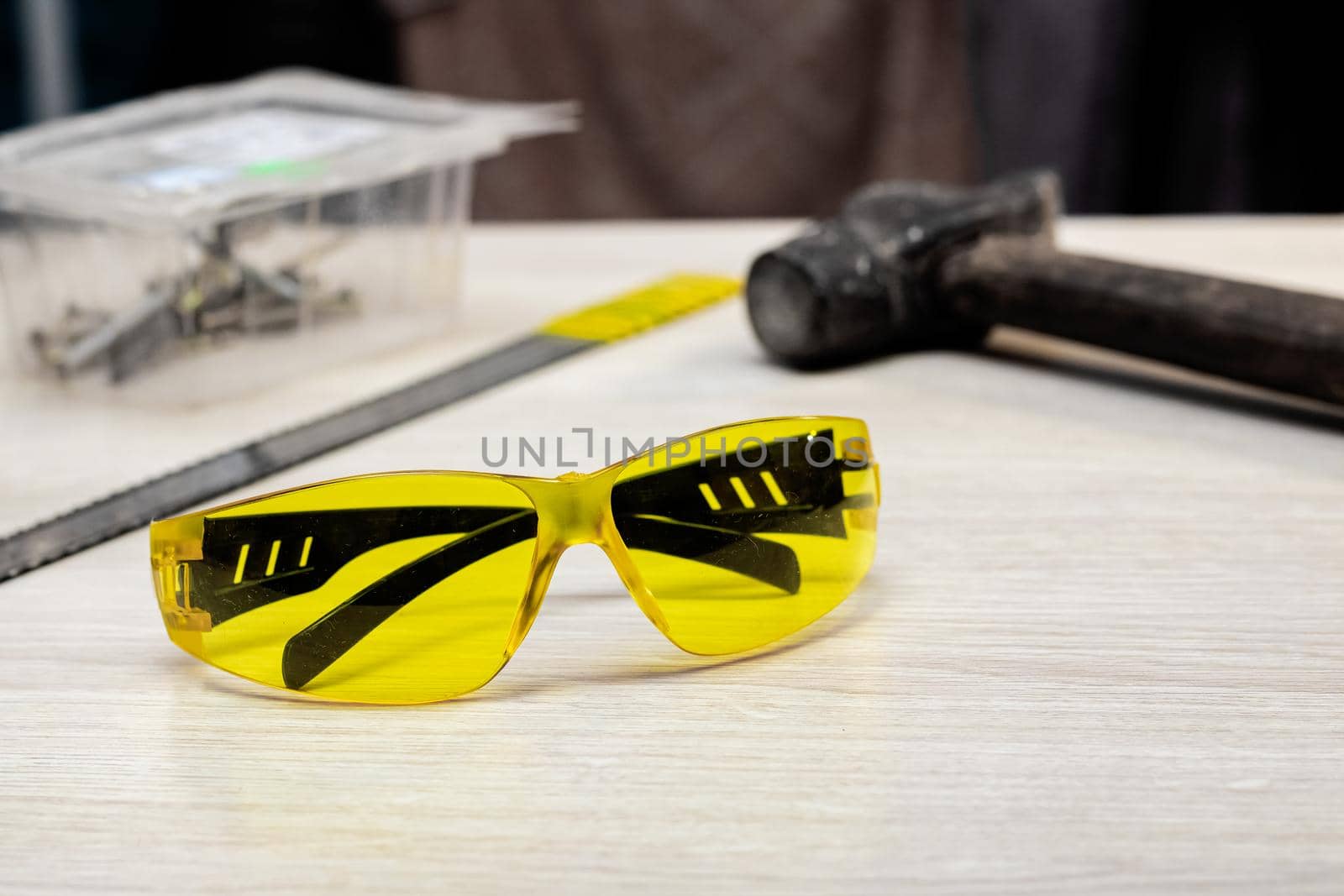 Yellow safety glasses and tools on wooden table close up