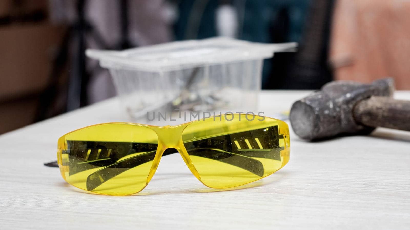 Yellow safety glasses and tools on wooden table close up