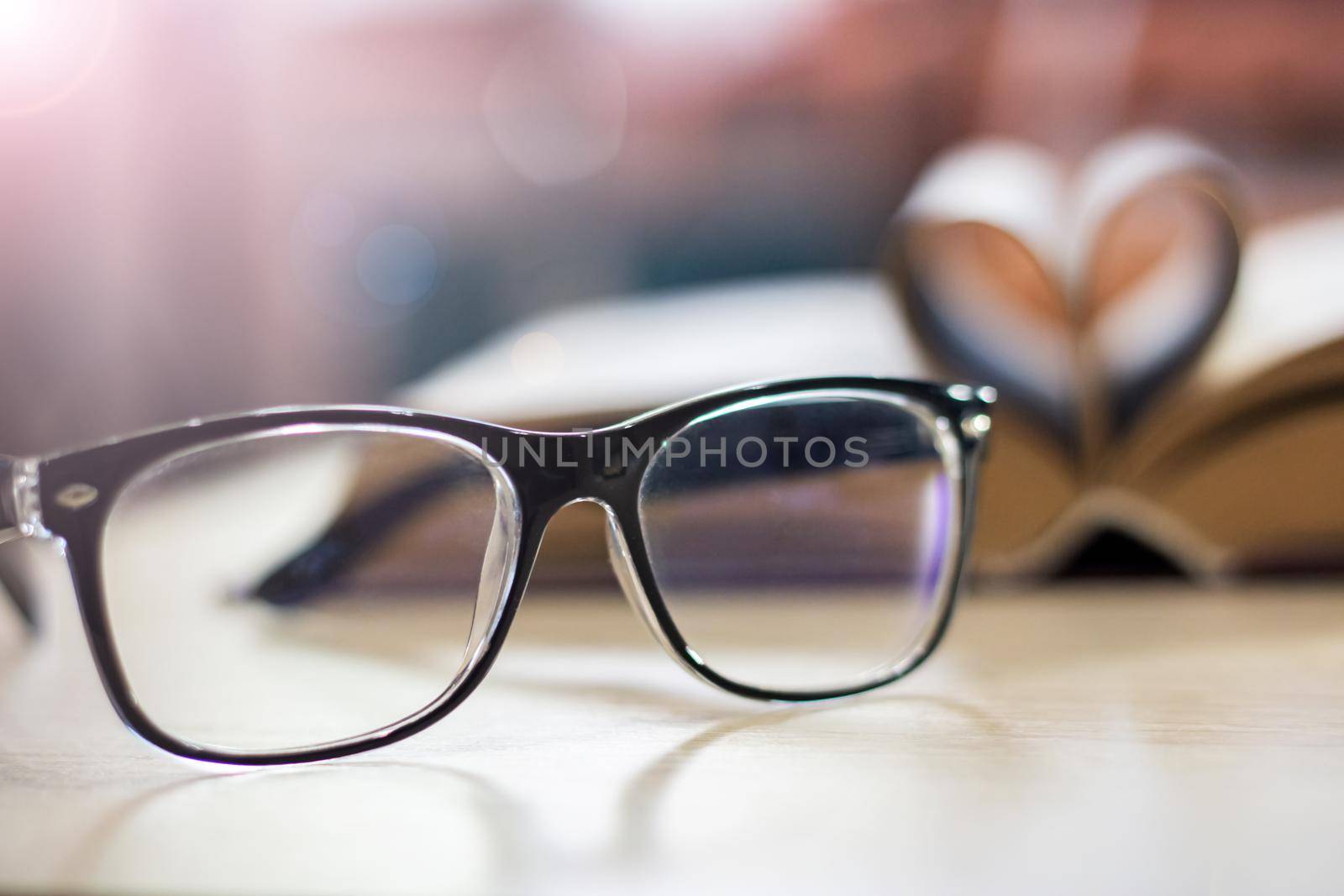 Black glasses on the background of the book in the light of the sun close up