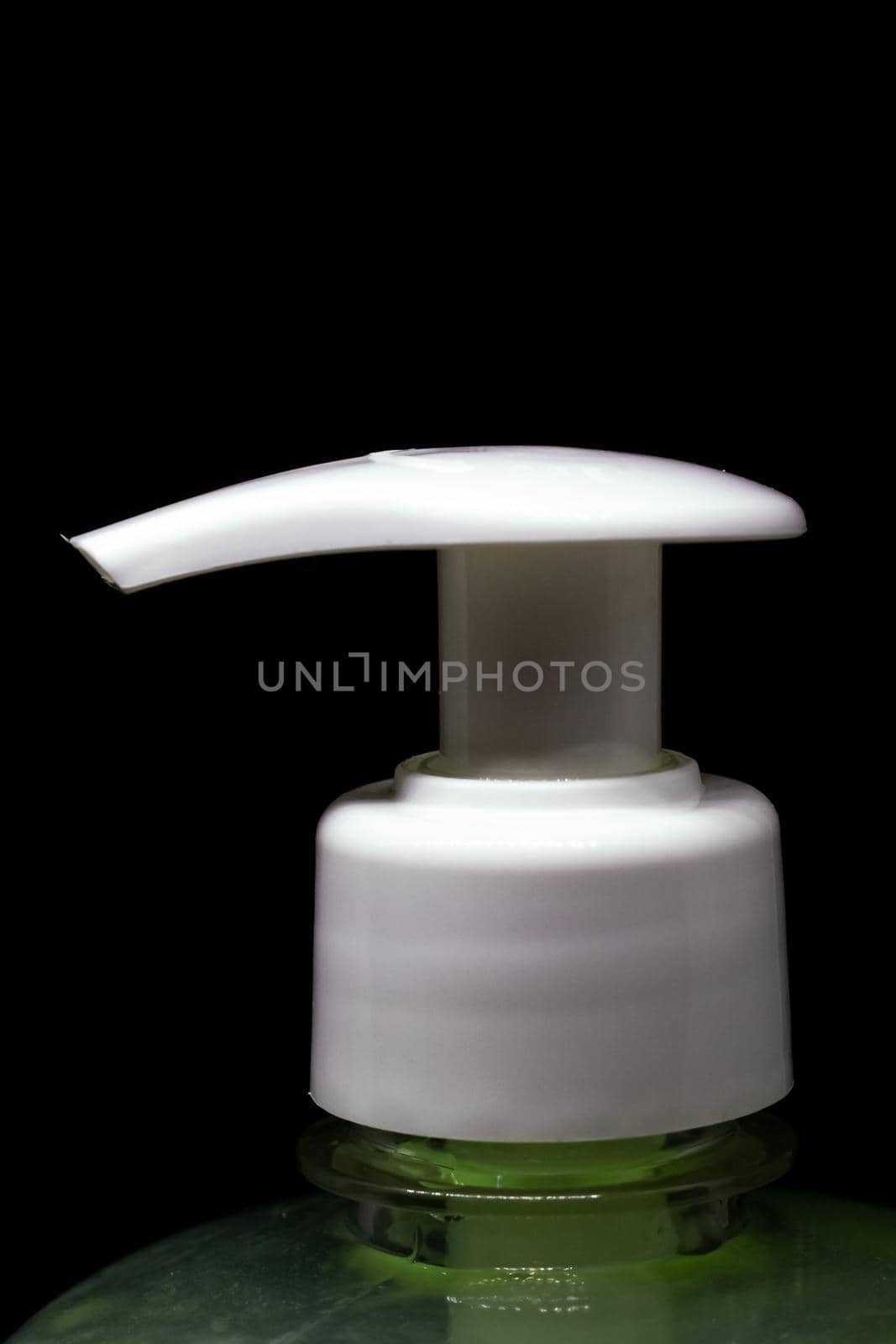 Dispenser and green liquid soap closeup, isolated on black background