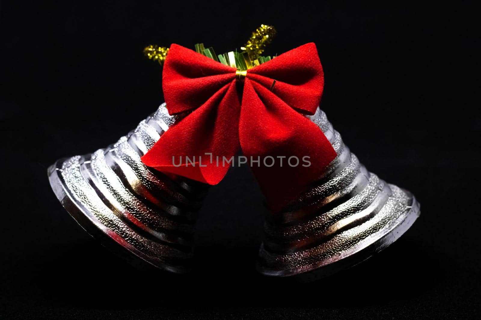 Christmas bells with a red bow on a black background close up