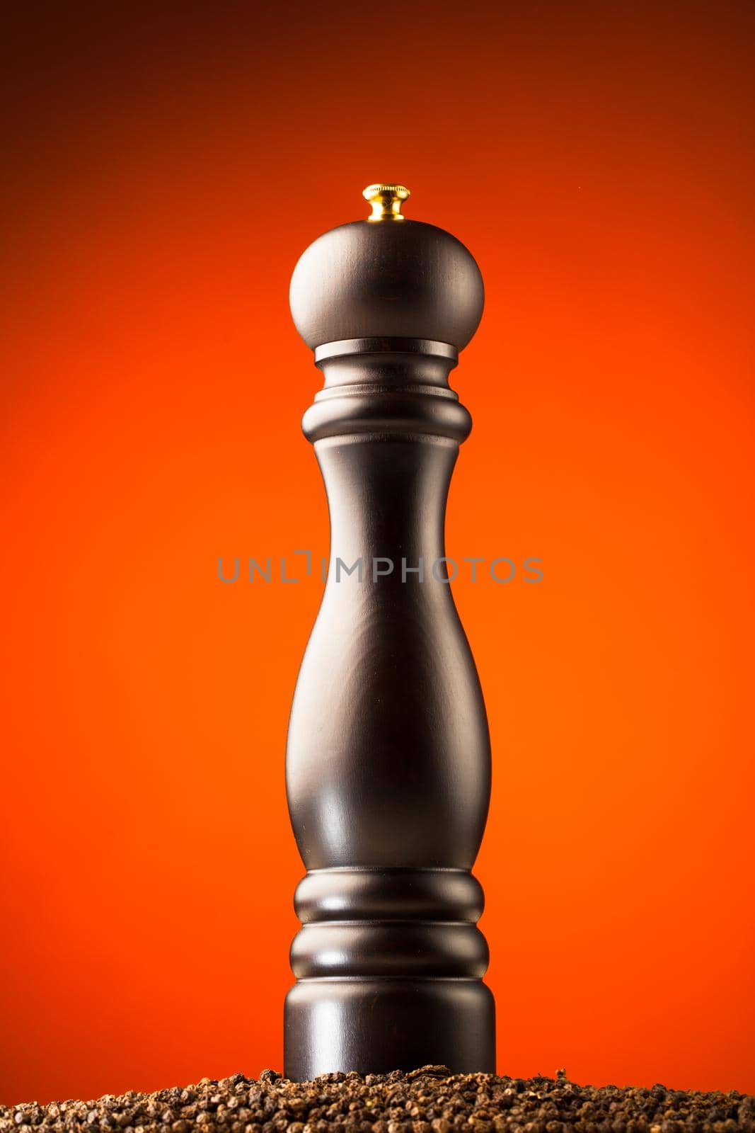 pepper mill and peppercorns heap, orange background by nikkytok