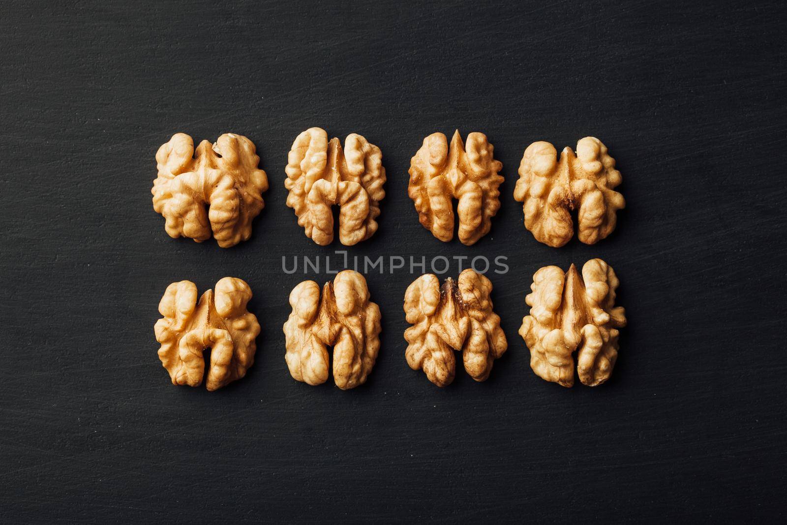 shelled walnuts in a row on black background