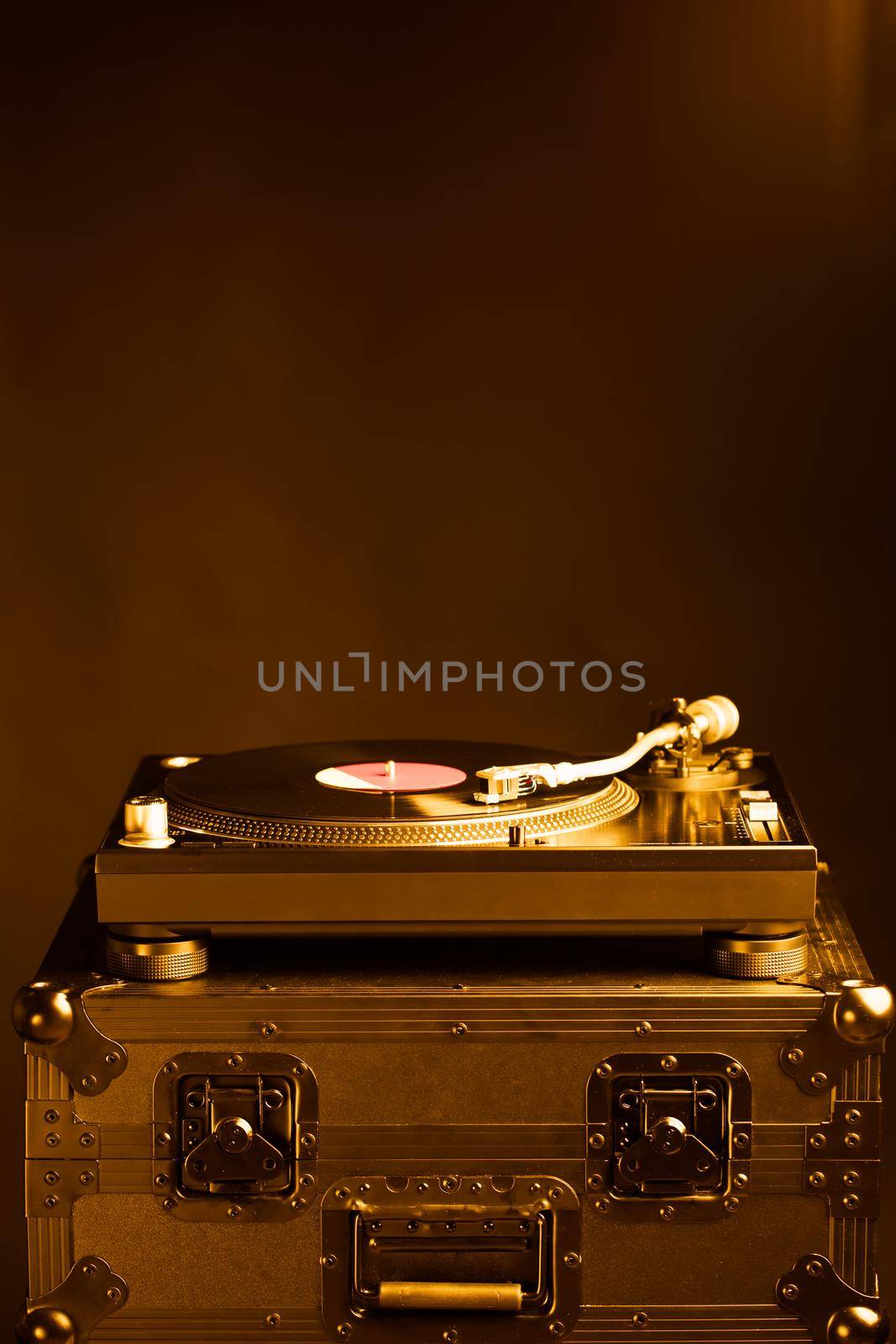 professional dj turntable on flight case, dark background, golden tone