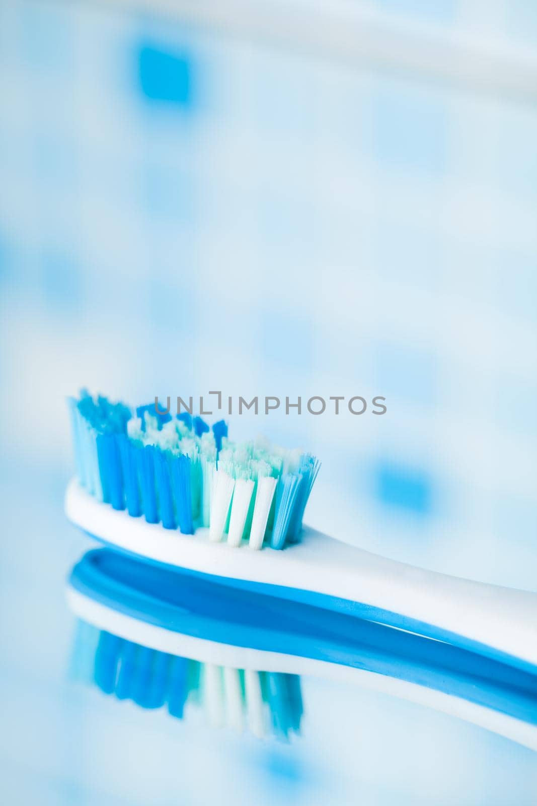 toothbrush on blue tile background with mirror reflection by nikkytok