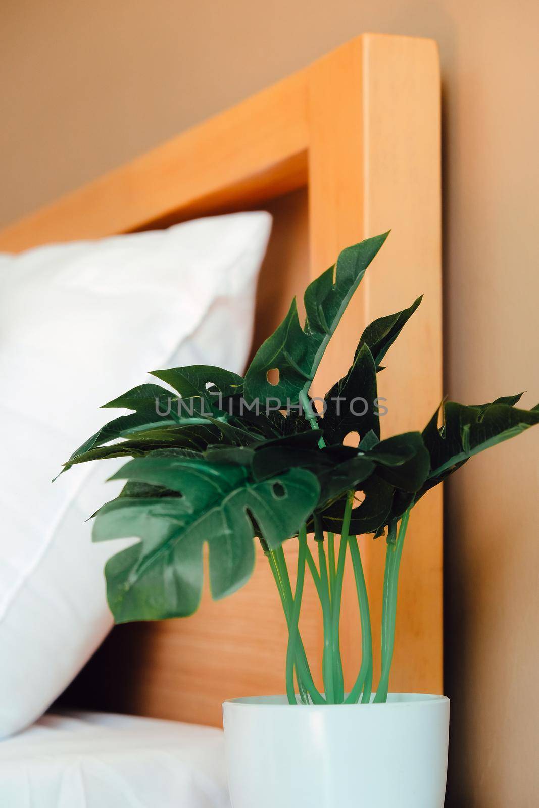 artificial plant decoration in bedroom. Modern white bed and pillow in the morning mood
