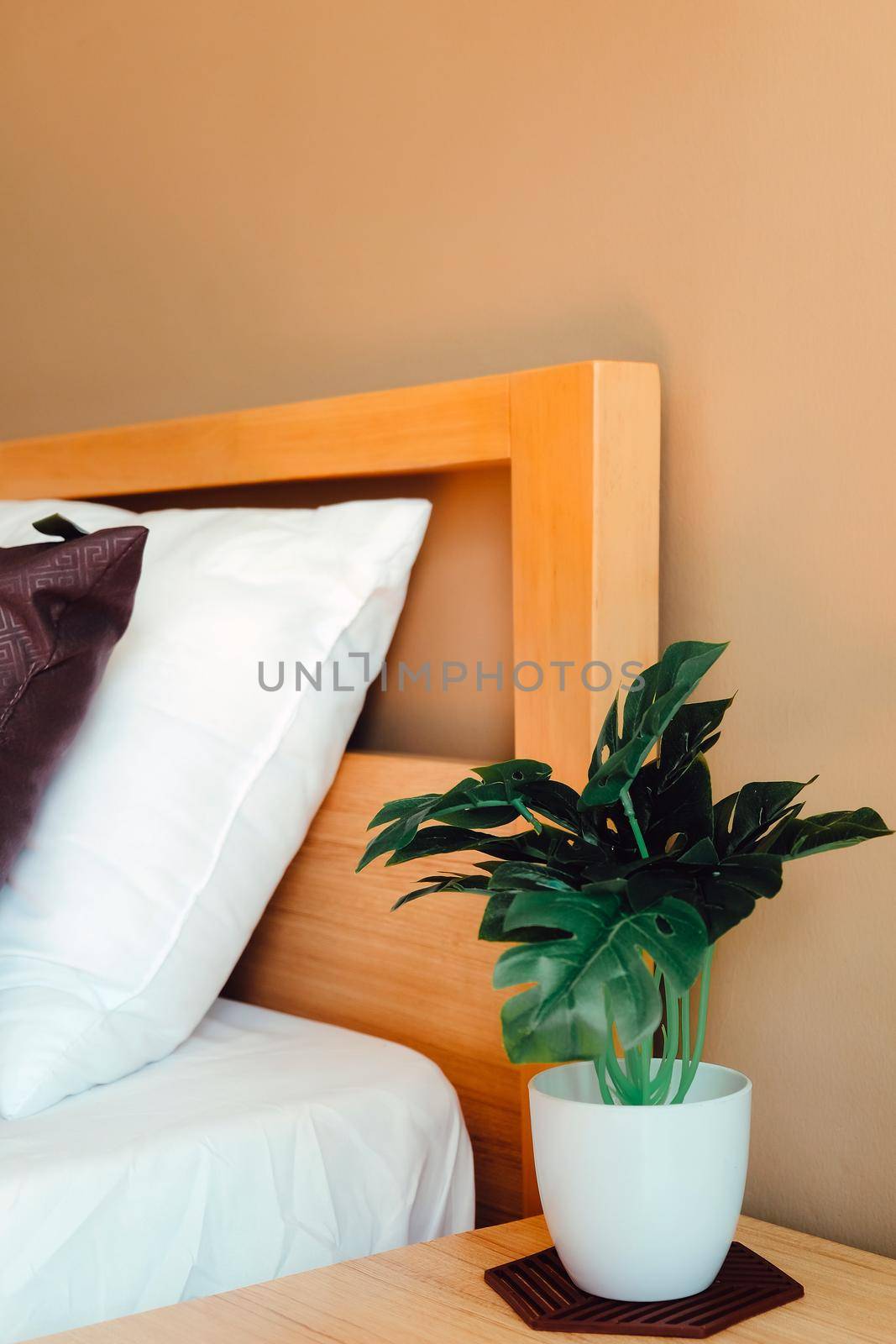 artificial plant decoration in bedroom. Modern white bed and pillow in the morning mood