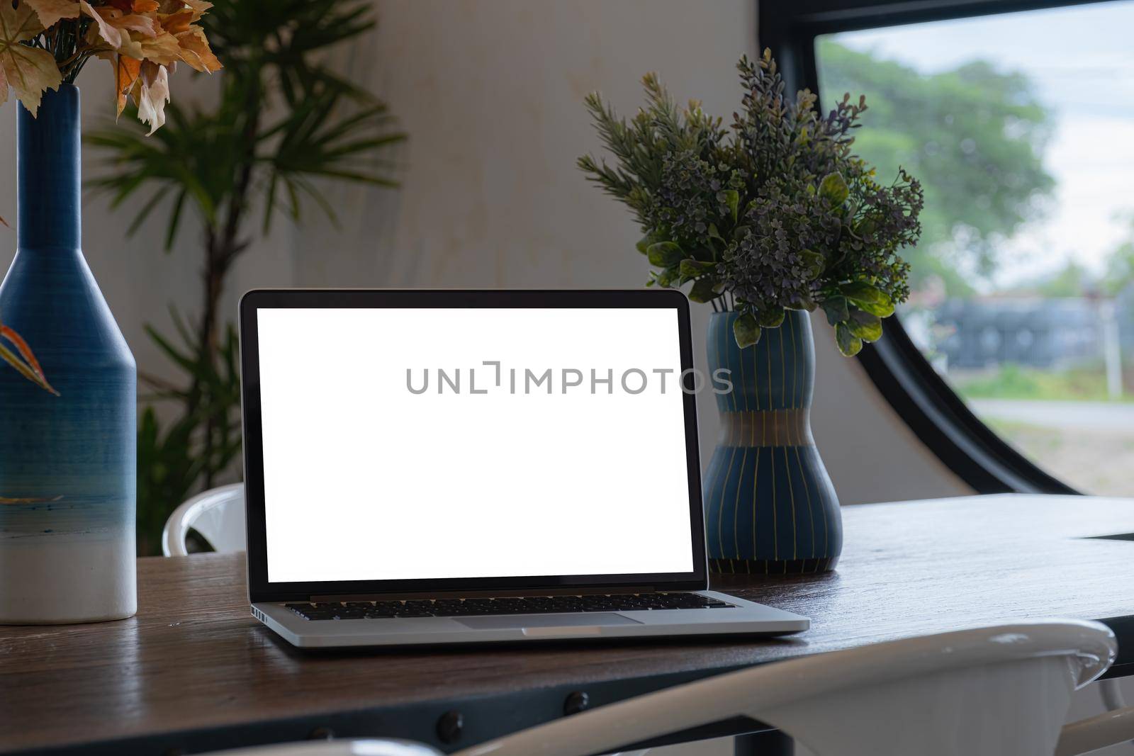 Laptop computer white screen on wooden desk in coffee shop. freelance and work from anywhere concept