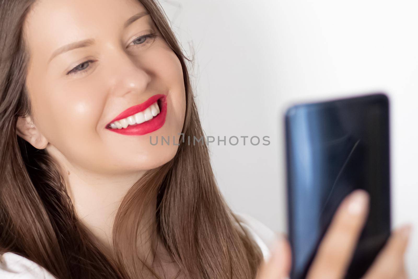 Happy smiling woman with smartphone having video call or taking selfie, portrait on white background. People, technology and communication concept by Anneleven