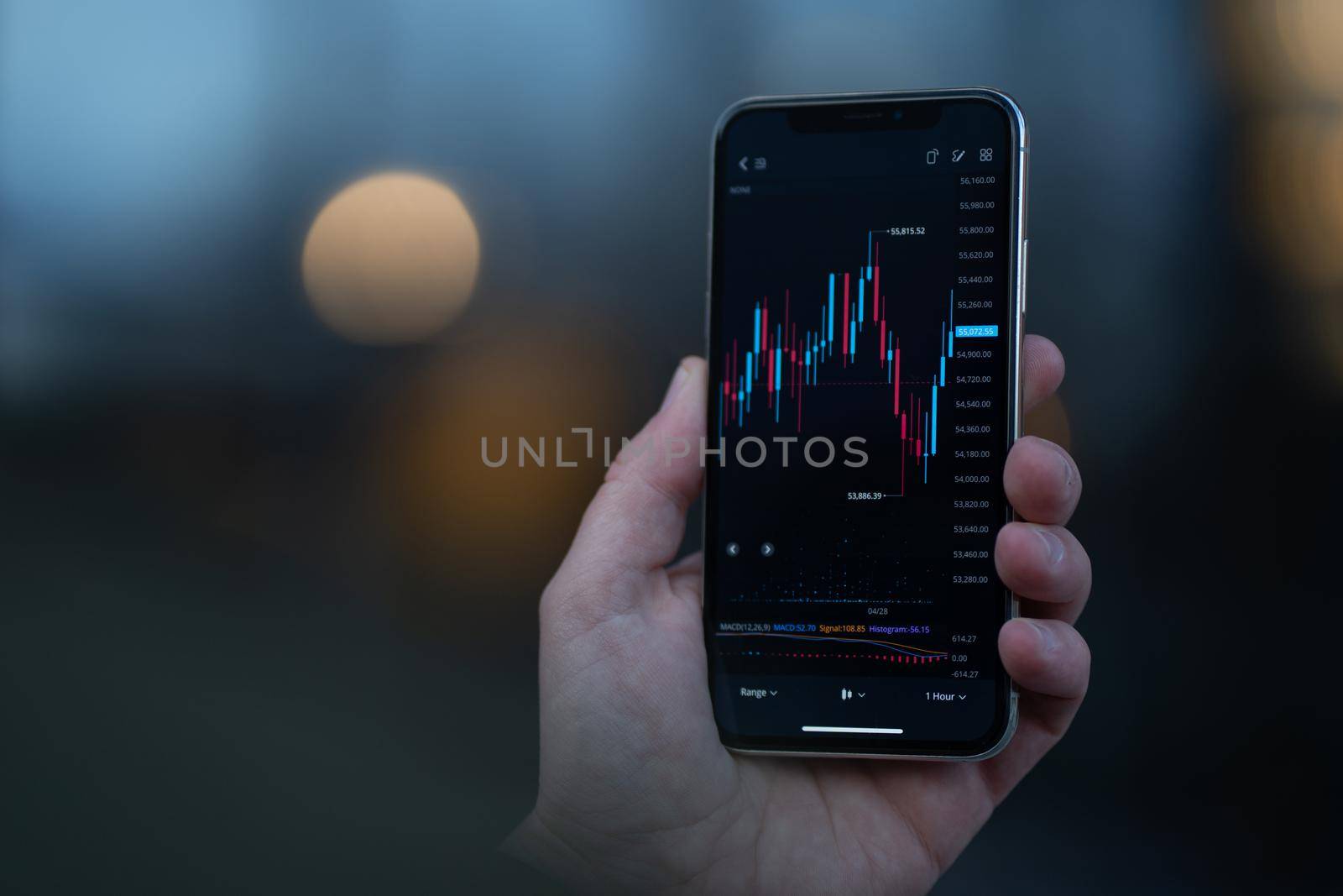 Trader looking at mobile phone with stock chart on screen by vkstock