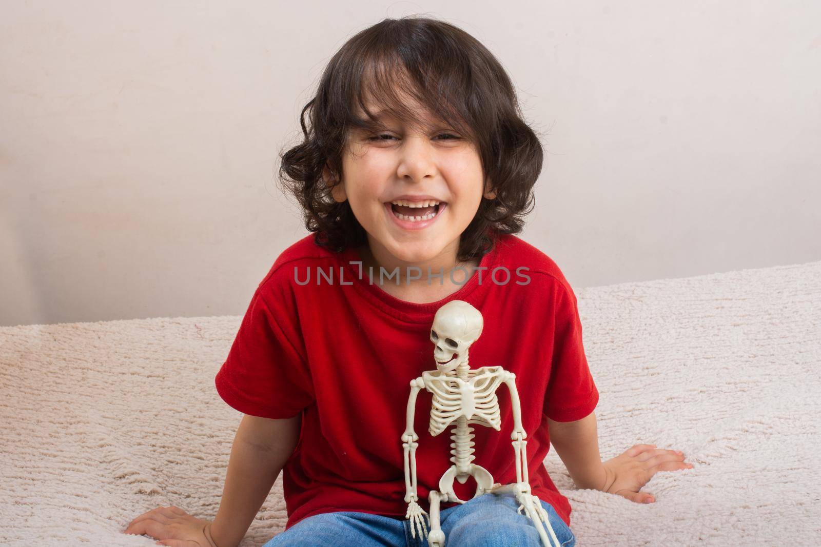Little boy holding a small size artificial skeleton in hand