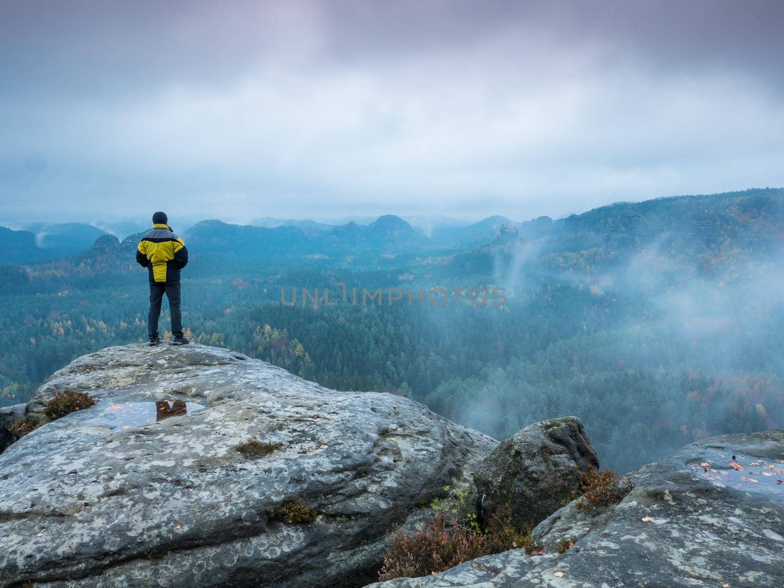 Tourist  looking over mountain valley with sunbeams at colorful autumn mist by rdonar2