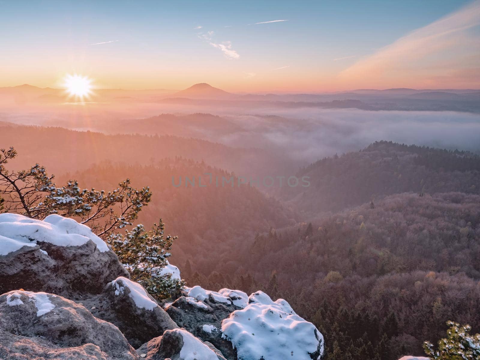 Mountain morning  landscape with fog and trees. Snowy rocks in foreground