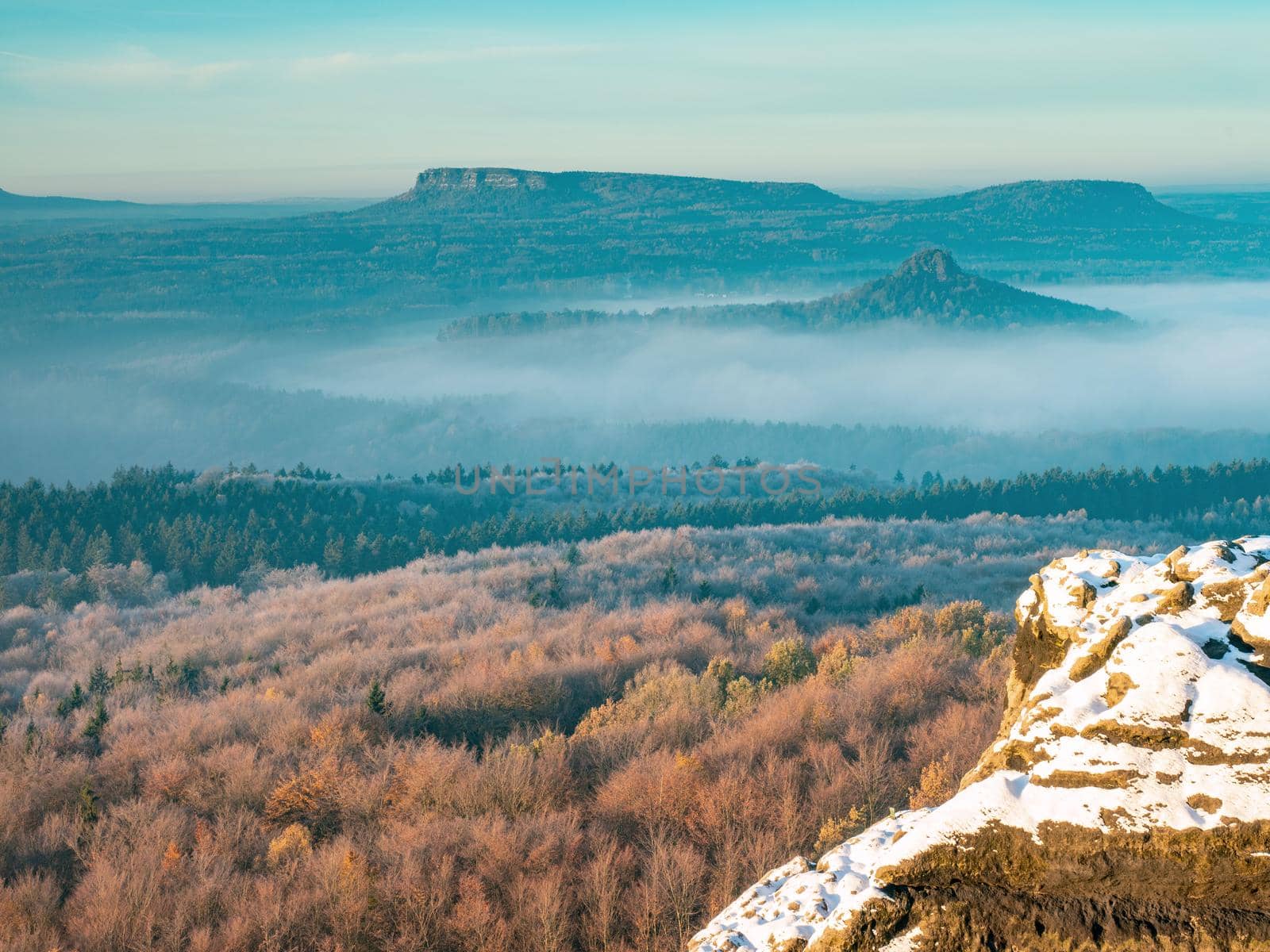 Snowy rocks above valley in Saxony Switzerland national park. Elbe river valley in chill morning