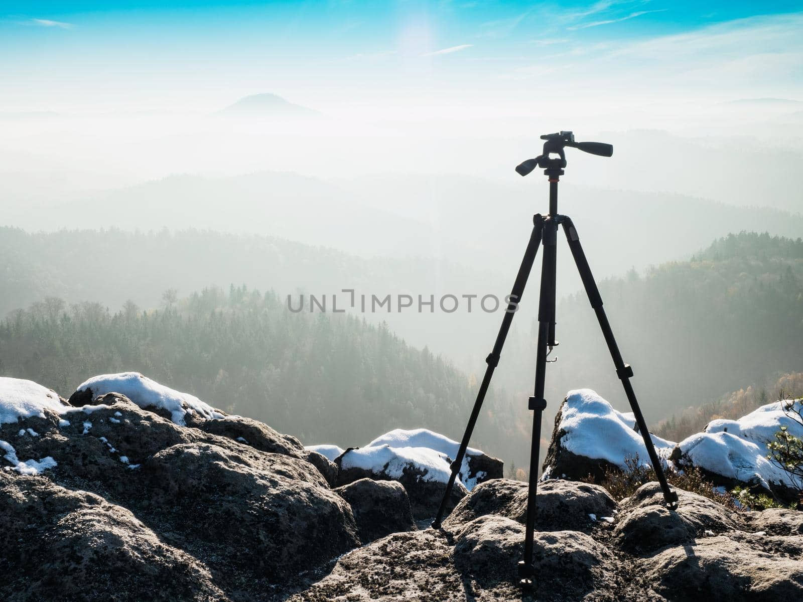 Empty tripod ready for creating time lapse in mountain winter landscape. Frozen morning outdoor 