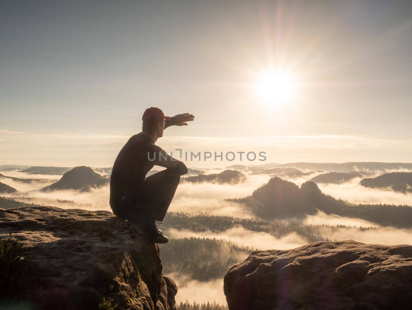 Man sitting at the peak of mountain on foggy morning.  Sit squatting at edge by rdonar2