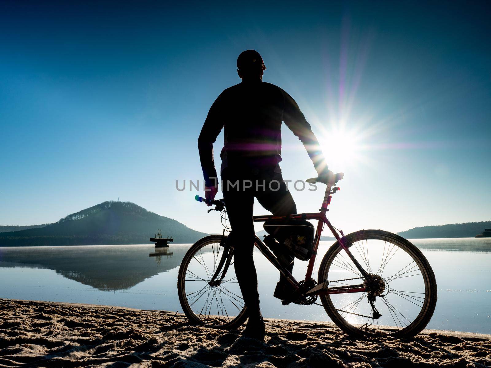 Biker with bike on beach. Rear View of Man Standing with a gravel bike  by rdonar2