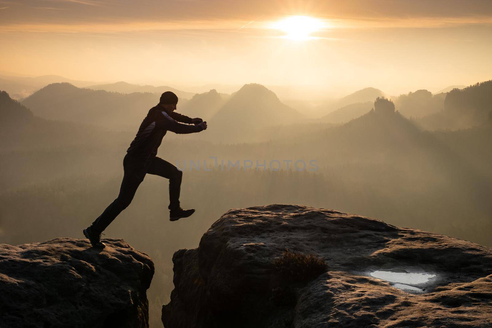 Strong mountain climber hiking and jumping over  the summit ridge  by rdonar2