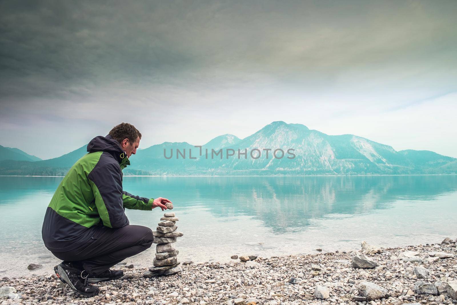 Cairn building. Hiker builds rock cairn from sharp dolomit stones at Alpine lake by rdonar2