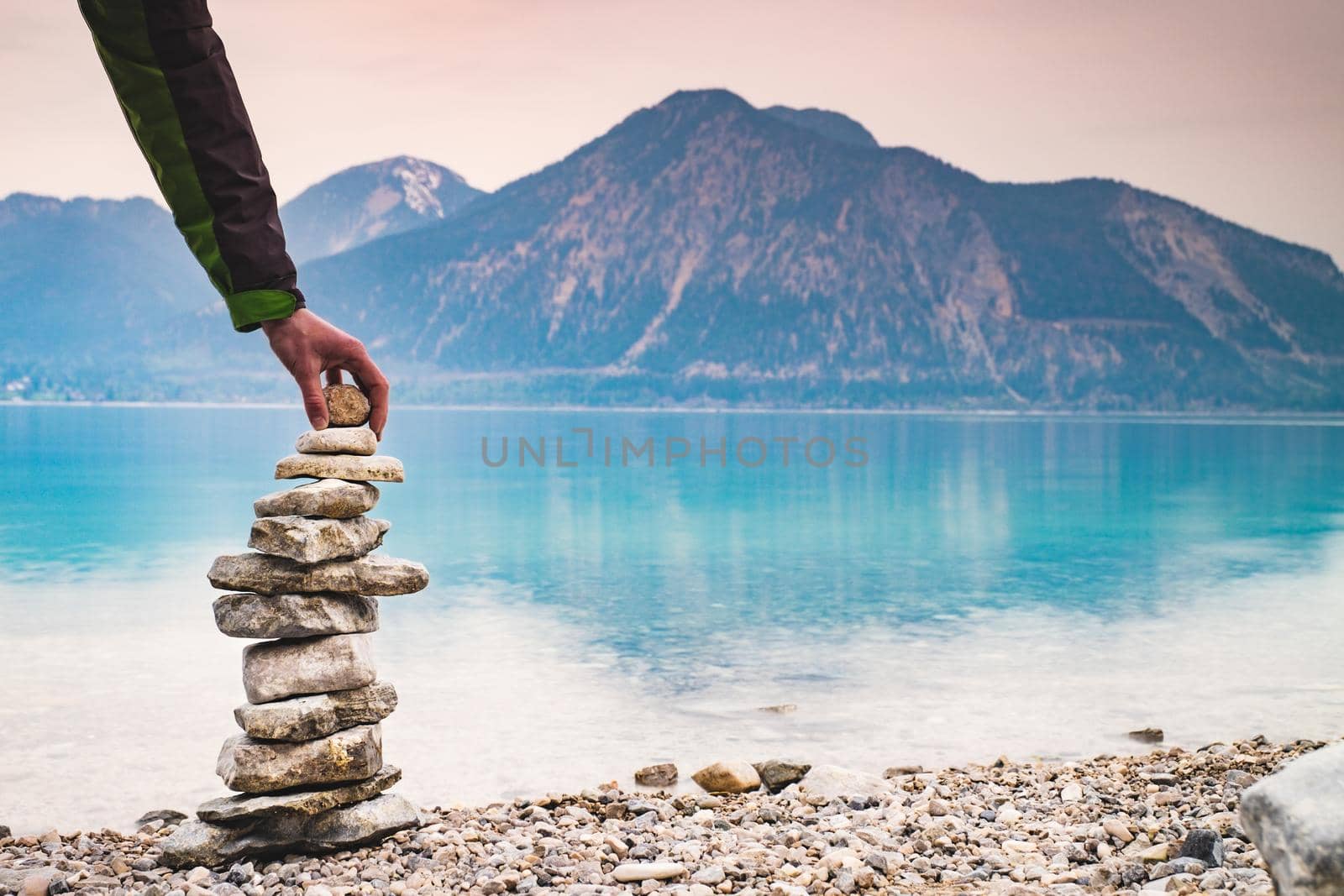 Cairn building. Hiker builds rock cairn from sharp dolomit stones at Alpine lake by rdonar2