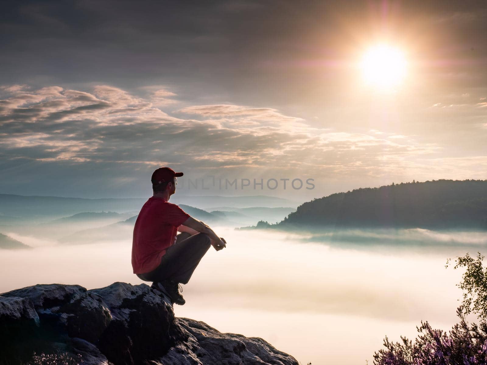 Man in sports clothing sit in squat on rocks enjoying autumn land view by rdonar2