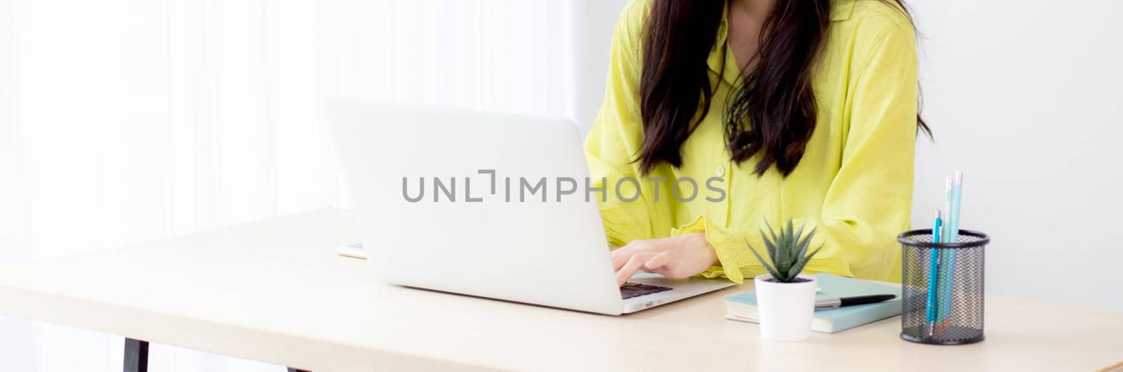 Young asian businesswoman working on laptop computer on desk at home office, freelance looking and typing on notebook on table, lifestyle of woman studying online, business and education concept. by nnudoo