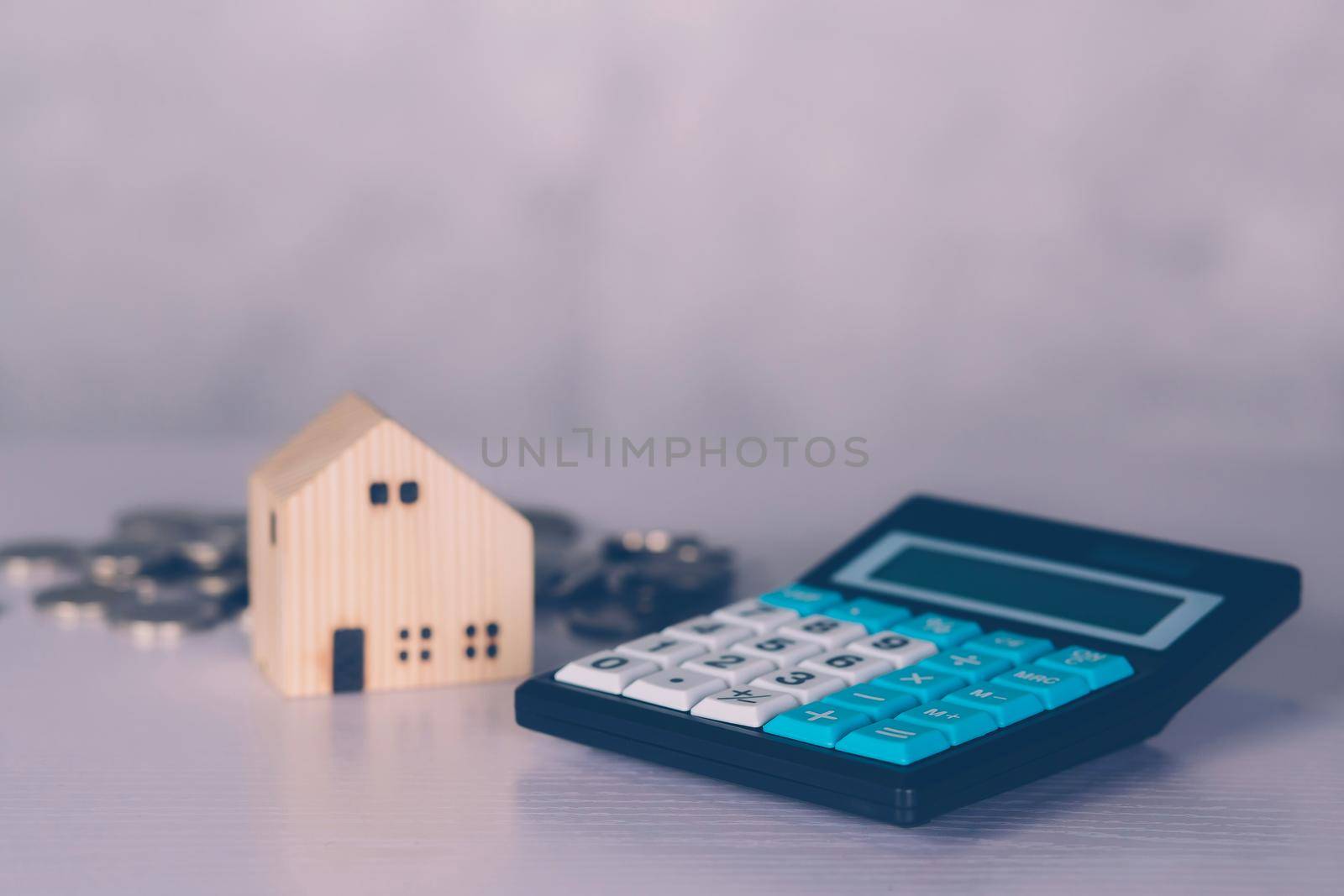 Investment about home with calculator and model house and coins on desk, property and real estate and mortgage, loan and finance, financial saving and account for residential, business concept.