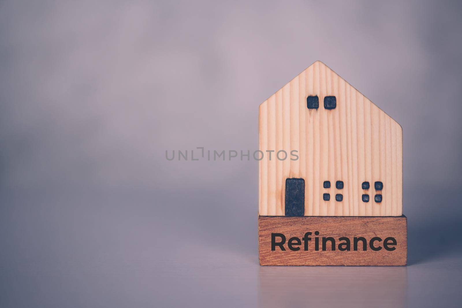 Wooden block with refinance word and house model about home and finance, loan and mortgage for real estate and property, residential and planning with budget, investment and earning, business concept.