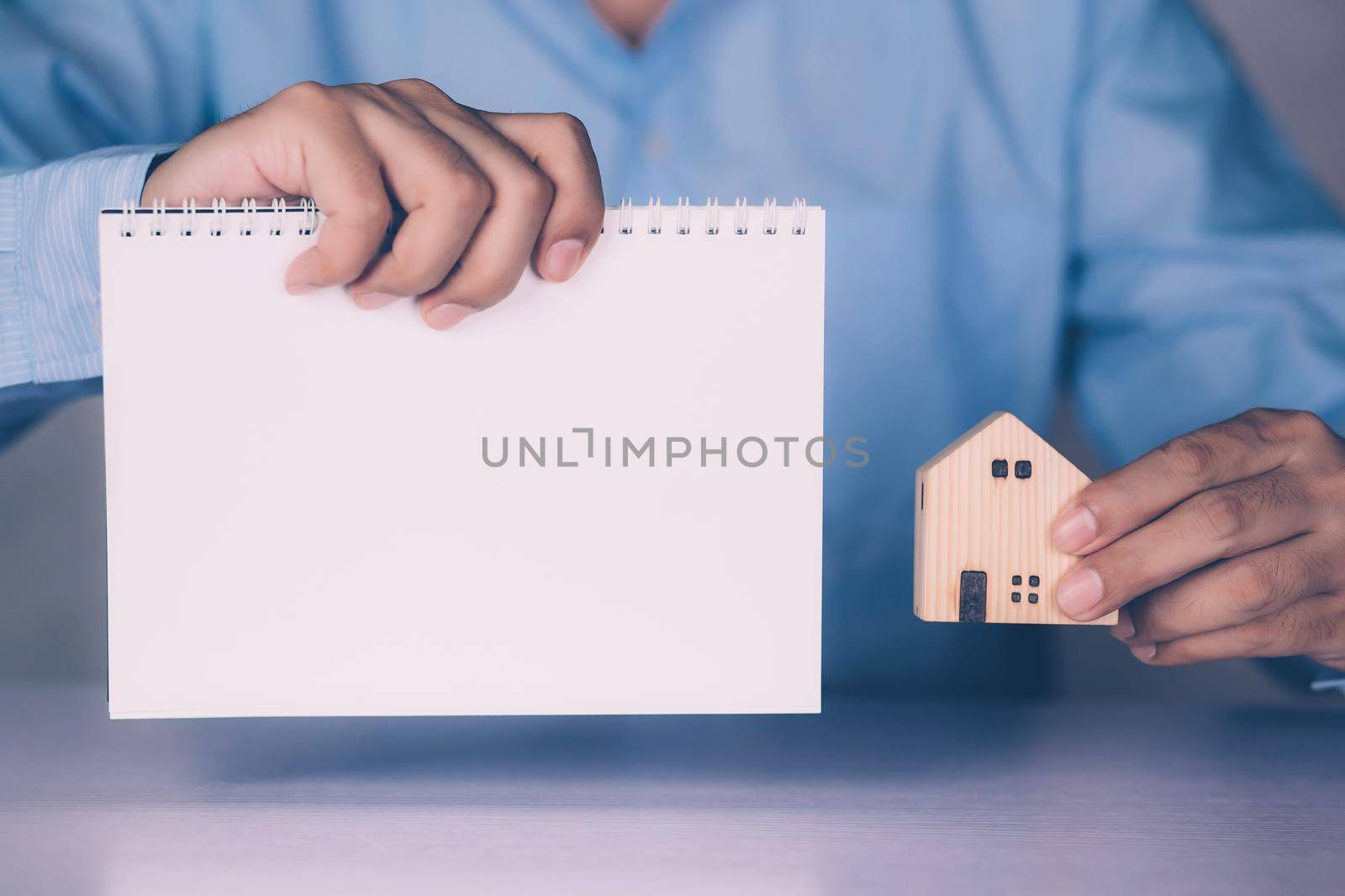 Hands of businessman holding home model and blank notebook, finance and residential, loan and mortgage of real estate, property and residence, investment with financial, business concept.