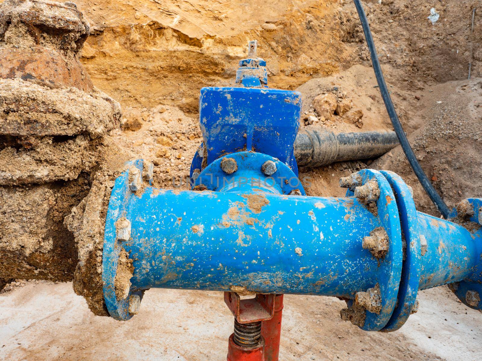 Large underground tubes and valves. Long water line downhill from water storage tank to city in the distance.