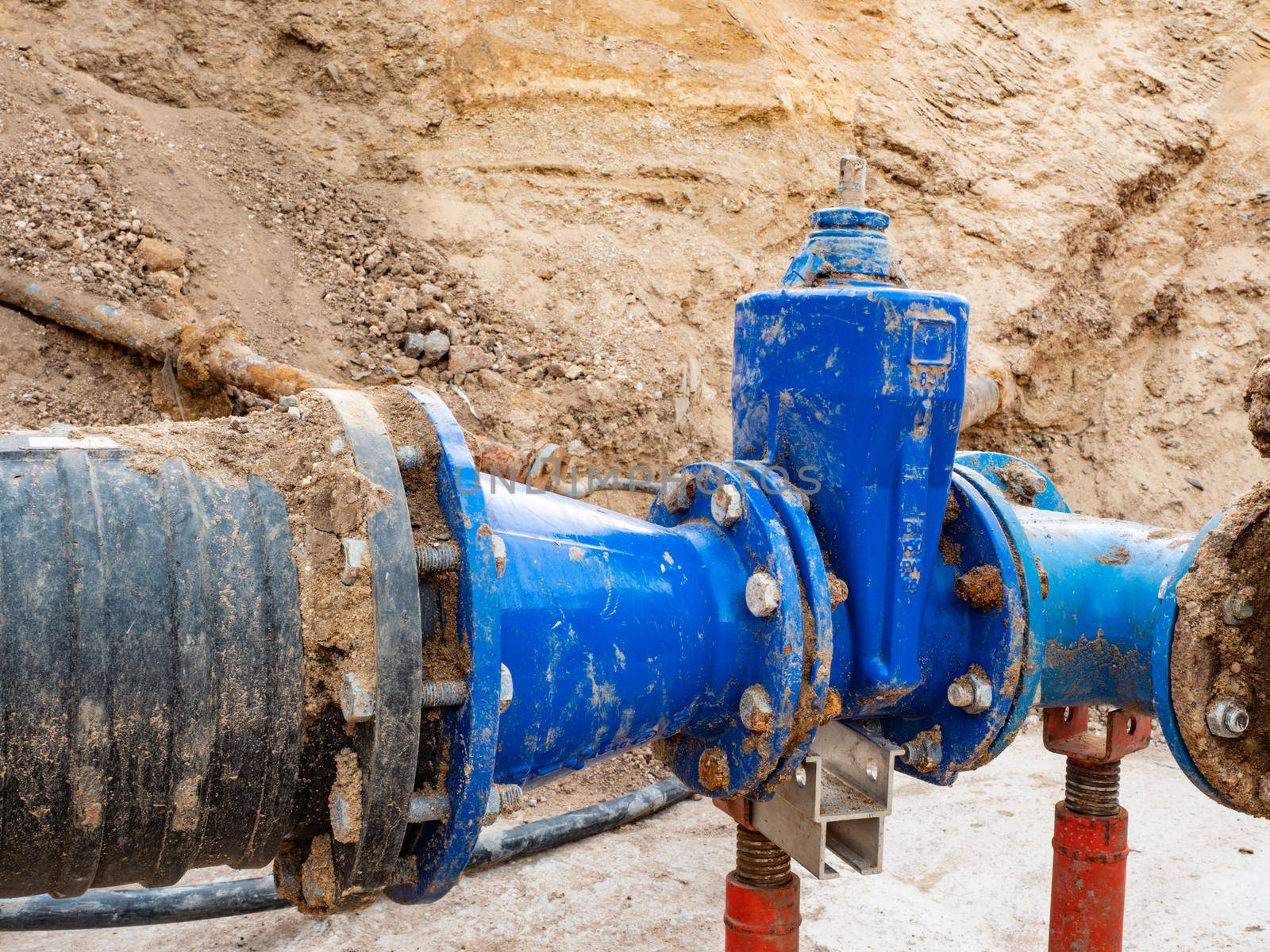 Large underground tubes and valves. Long water line downhill from water storage tank to city in the distance.