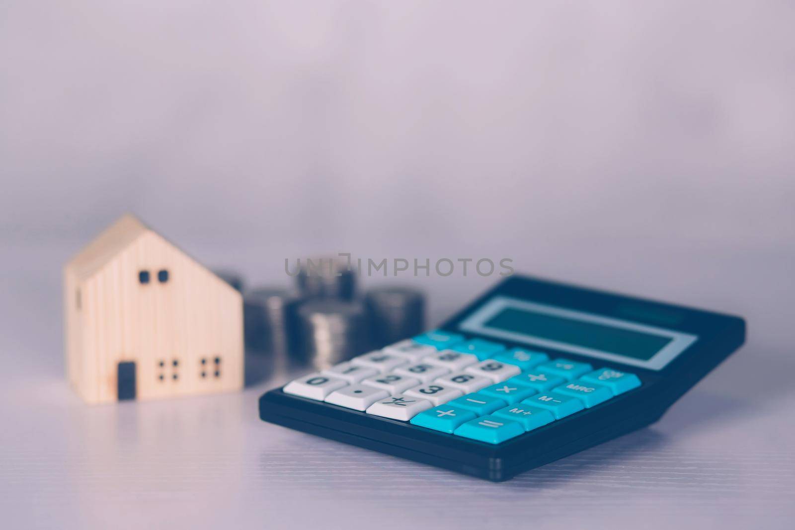 Investment about home with calculator and model house and coins on desk, property and real estate and mortgage, loan and finance, financial saving and account for residential, business concept. by nnudoo