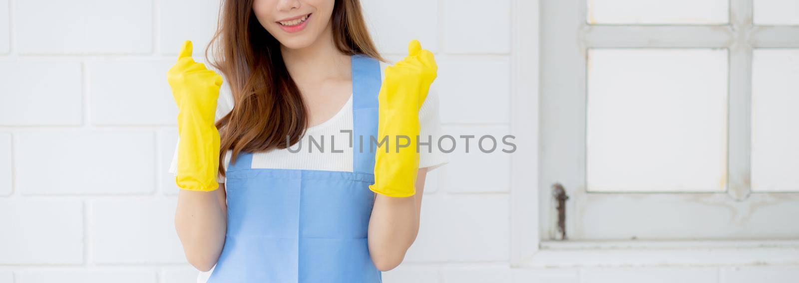 Portrait young asian woman is housekeeper in rubber gloves and apron for protection at home, uniform of maid, cleaning and washing, girl standing worker positive, one people, lifestyle concept. by nnudoo