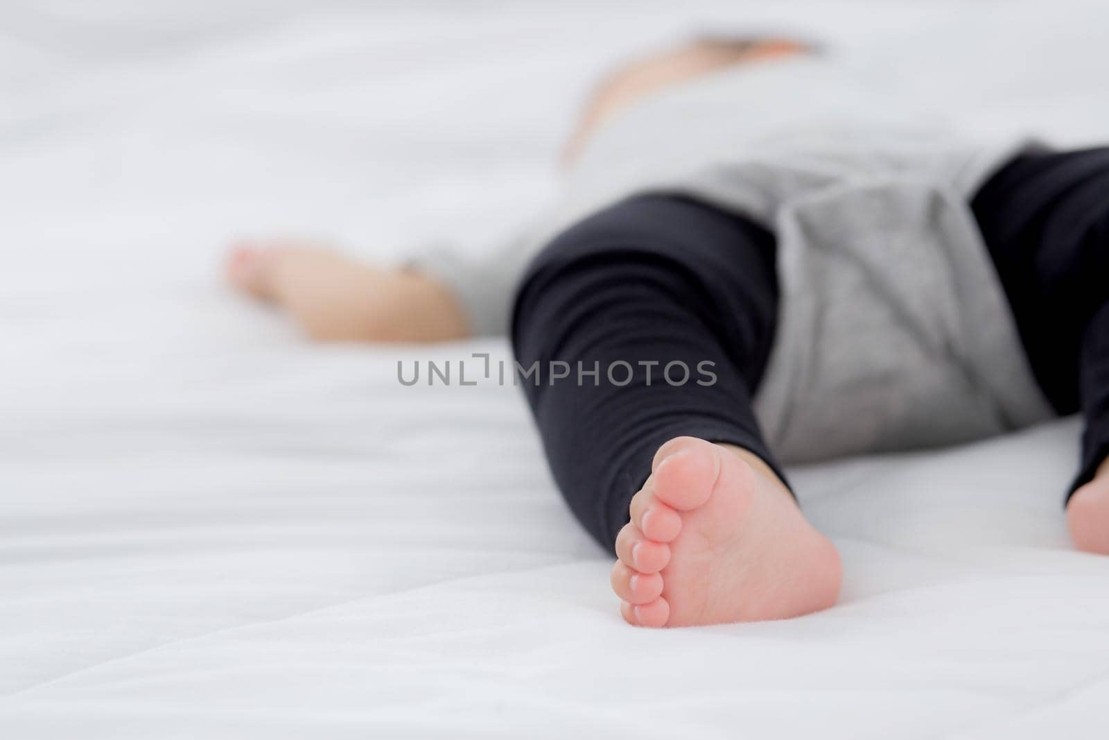 Closeup foot of asian little baby girl sleeping on bed in the bedroom at home, newborn napping with cozy and relax, infant innocence in bedtime, happy toddler cute, growth of child and emotion.