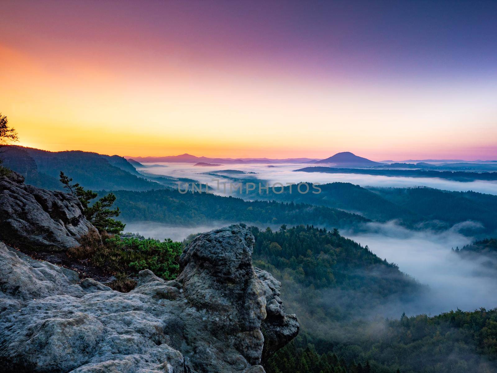 Sunset at Mountains.  Deep valley full of colorful trees within autumn season.