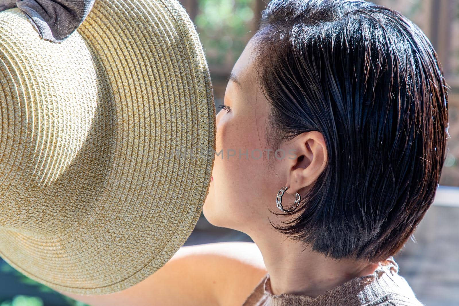 Young asian woman and short hair holds the brim of the Hat close-up.  by tosirikul