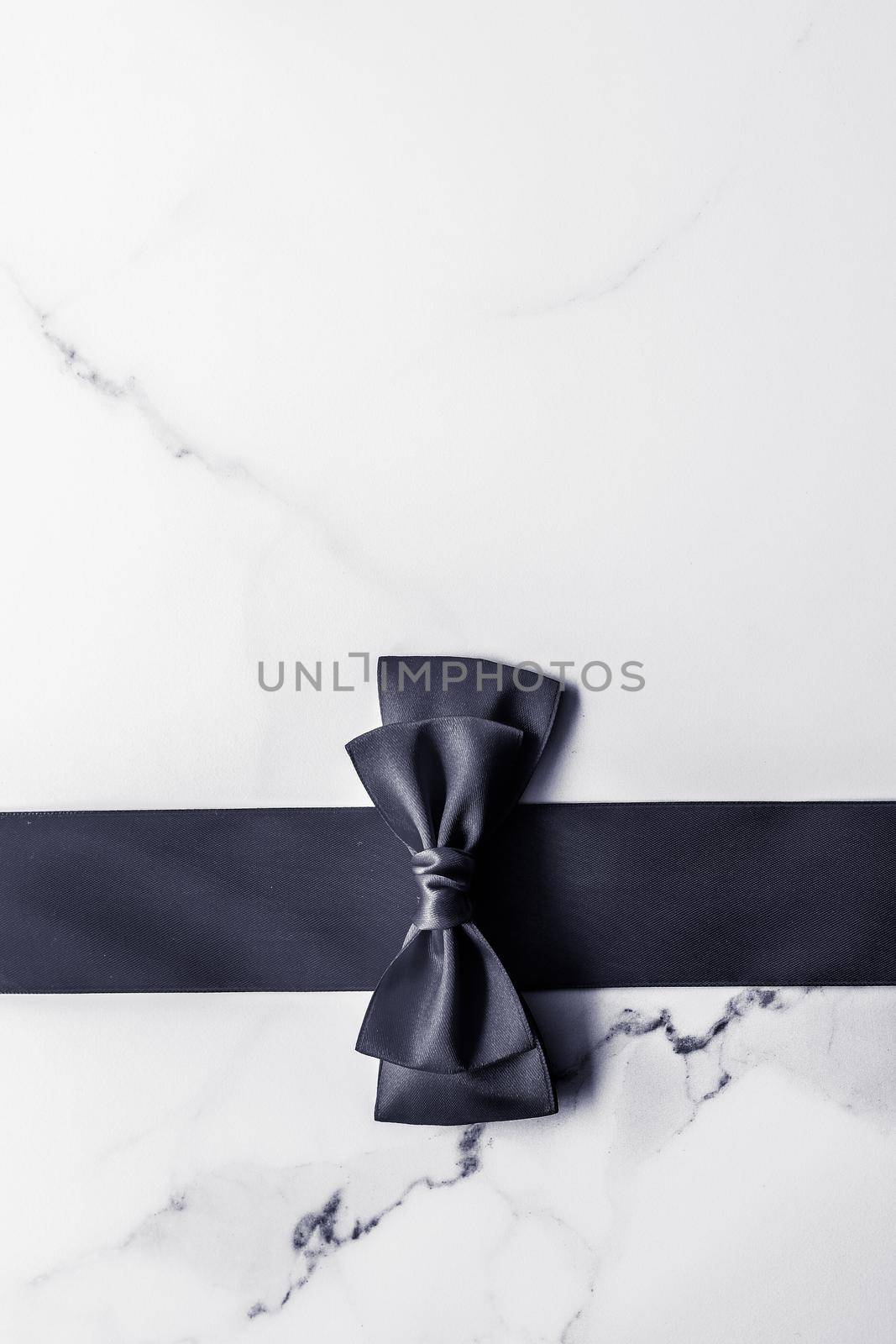 Holiday gift, decoration and sale promotion concept - Black silk ribbon and bow on marble background, flatlay