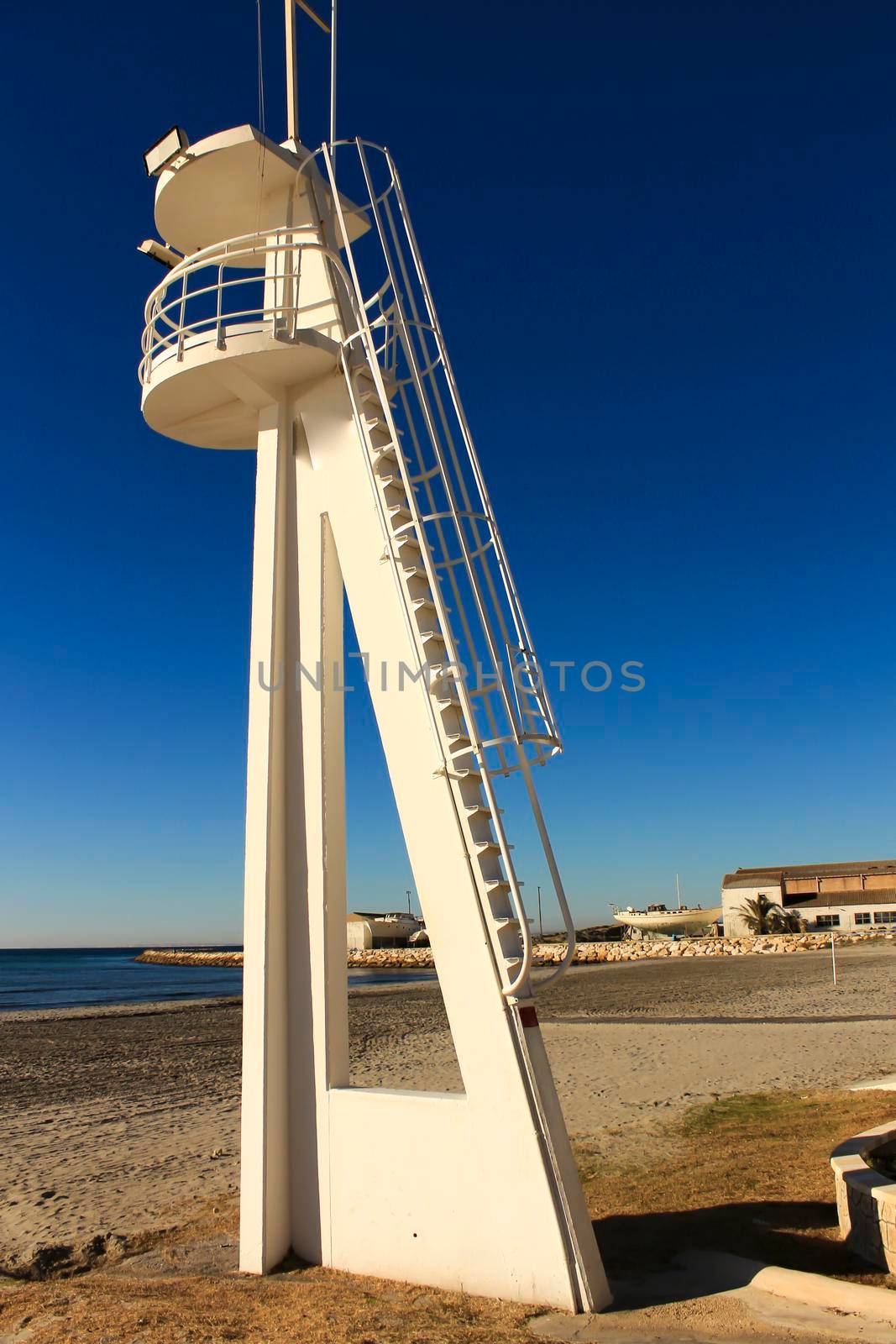 Lifeguard tower on a quiet and lonely beach in a sunny day in southern Spain, Alicante. Palm trees in the background.